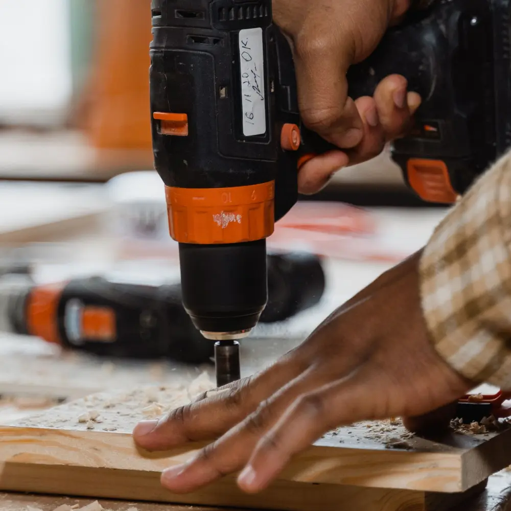 Close up of a cordless drill driving a screw into a board during a repair